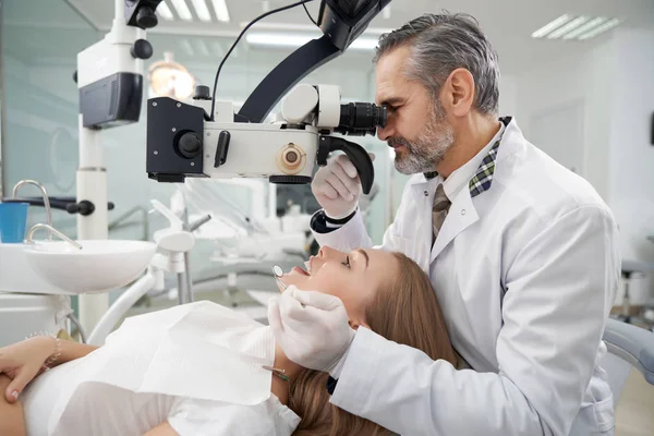 Dentista che utilizza il microscopio dentale per l'esame . — Foto Stock