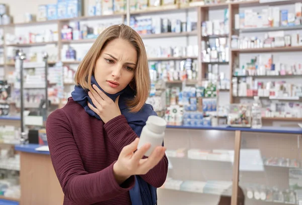 Mujer enferma mirando botella burla con pastillas en la farmacia . — Foto de Stock