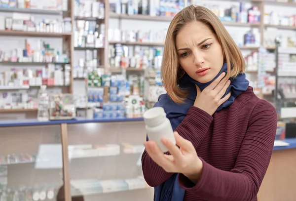 Woman frowning and holding bottle mock in drugstore.
