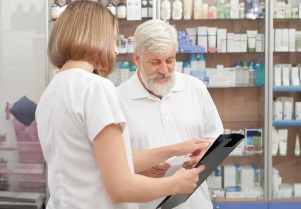 Farmacéutico ayudando a hombre mayor con medicamentos . — Foto de Stock