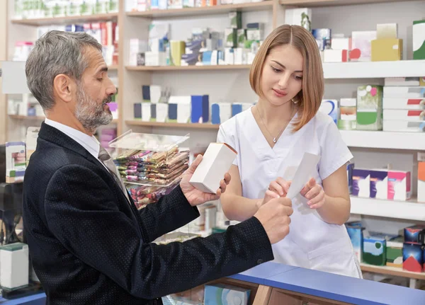 Donna che lavora in farmacia con un cliente maschio . — Foto Stock