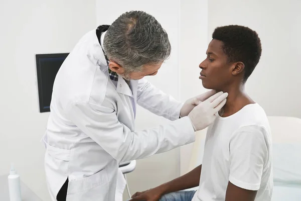 Médico examinando cuello de paciente africano . — Foto de Stock