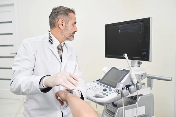 Médico fazendo exame de ultra-som do pulso patinetes . — Fotografia de Stock