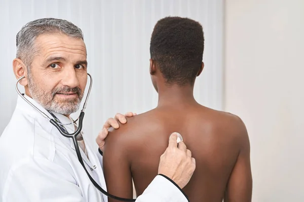 Médecin posant, tenant le stéthoscope sur le dos du patient . — Photo