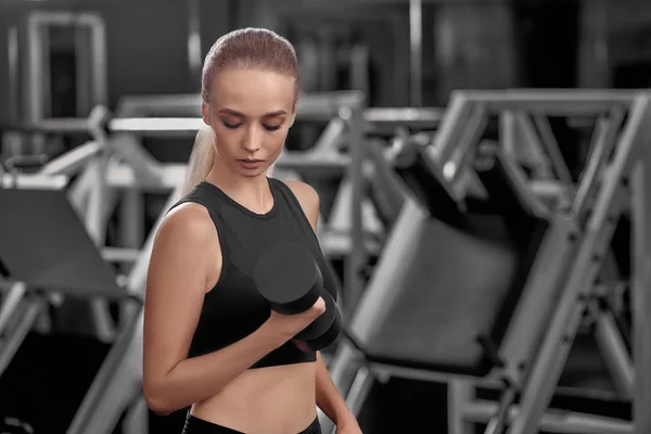 Loira com corpo esportivo levantando halteres . — Fotografia de Stock