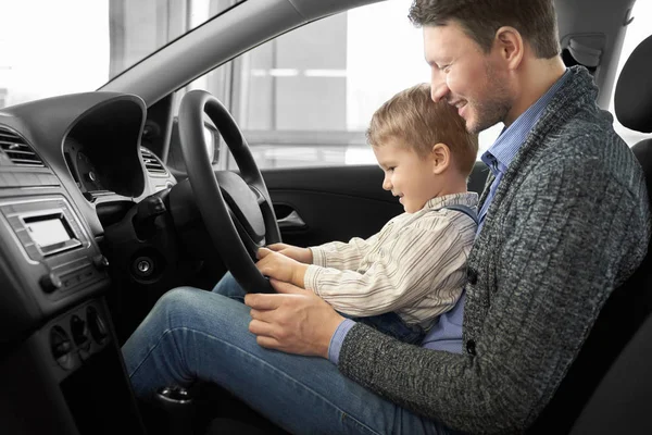 Отец и сын сидят на водительском сидении в новом автомобиле . — стоковое фото