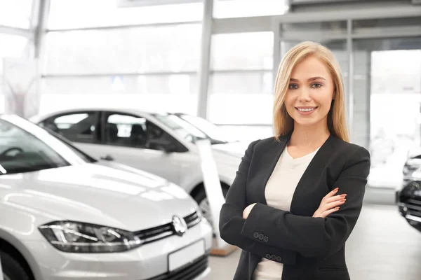 Bonito negociante de carro feminino posando em concessionária . — Fotografia de Stock