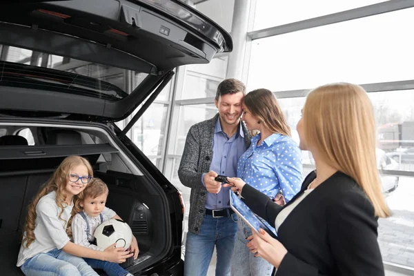 Familjen köper auto i återförsäljaravtalet, manager ger bilnycklar. — Stockfoto