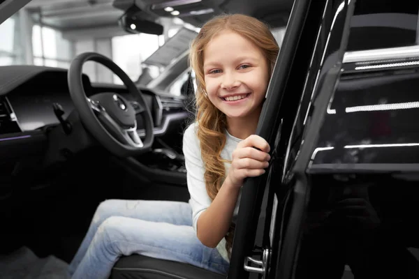 Sorrindo menina sentada em motoristas assento de carro novo . — Fotografia de Stock