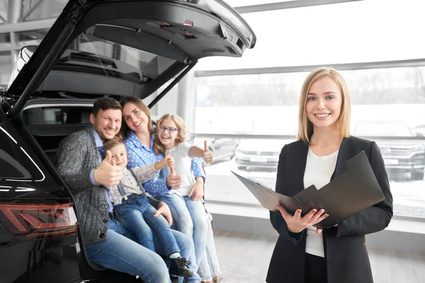 Carro revendedor posando na câmera com a família, compradores de carro novo . — Fotografia de Stock