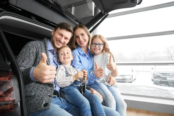 Família feliz mostrando polegares para cima, posando no porta-malas do carro . — Fotografia de Stock