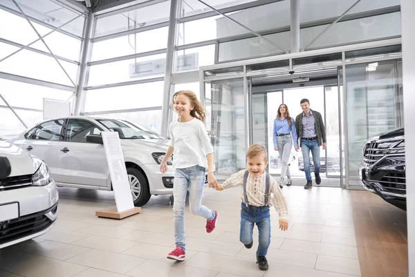 Familjen kommer in bilfirma, glada barn kör. — Stockfoto