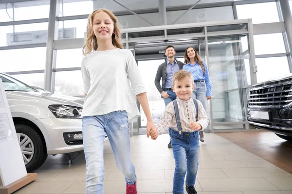 Barn och föräldrar i bil center showroom. — Stockfoto