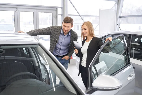 Distribuidor femenino de automóviles que muestra el automóvil al comprador potencial . —  Fotos de Stock