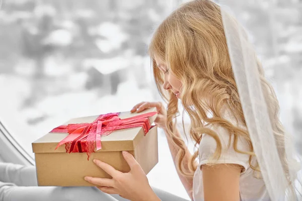 Прекрасна дівчина відкриває ремесло подарункова коробка з червоним бантом . — стокове фото