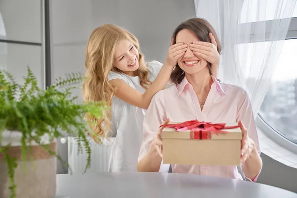 Дочка дарує подарунок і закриває очі матері . — стокове фото