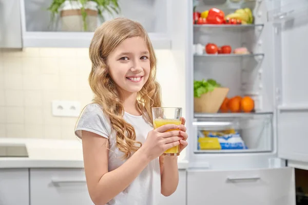 Hübsches Mädchen hält Glas mit Orangensaft und lächelt. — Stockfoto