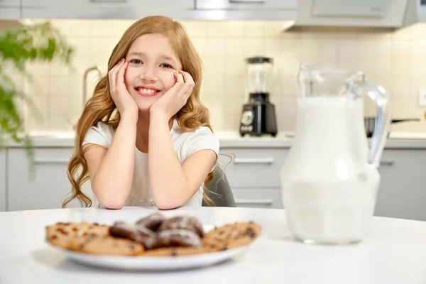 Criança posando, biscoitos americanos e jarro de leite na mesa .. — Fotografia de Stock