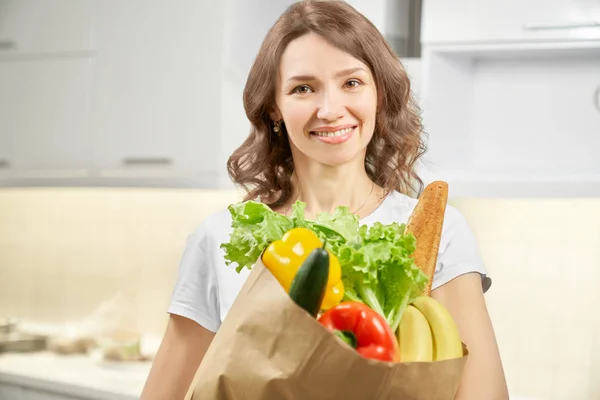 Hübsche Frau posiert mit Papiertüte voller Gemüse. — Stockfoto