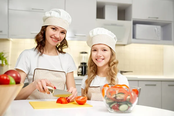 Moeder en dochter poseren in keuken, koken salade. — Stockfoto