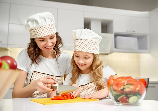 Moeder en dochter snijden groenten voor frisse salade. — Stockfoto