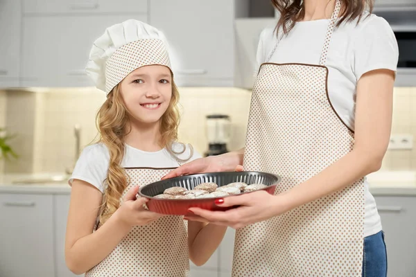 Chica y madre sosteniendo la forma de hornear con cupcakes . — Foto de Stock