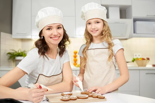 Mother and daugter decorating cookies with sugar glaze.