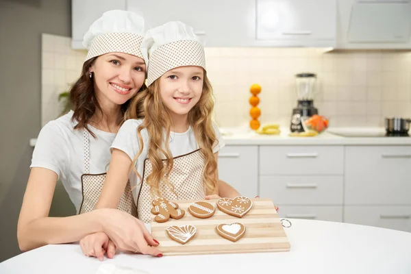 Mama și fiica fericite care arată bord cu cookie-uri de ghimbir . — Fotografie, imagine de stoc