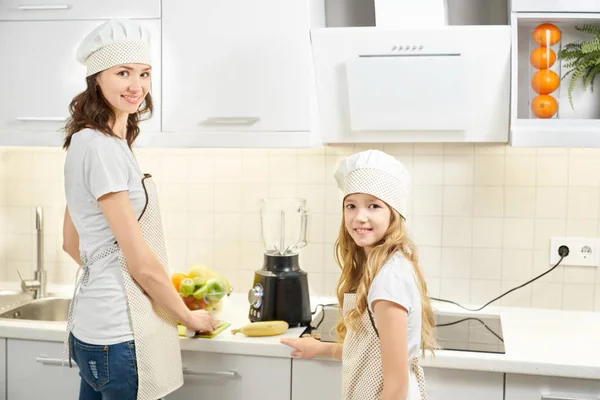 Mãe e filha posando na cozinha com dispositivos modernos . — Fotografia de Stock