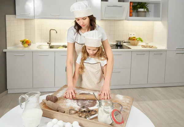 Mãe ensinando filha a espremer massa de farinha de biscoitos . — Fotografia de Stock