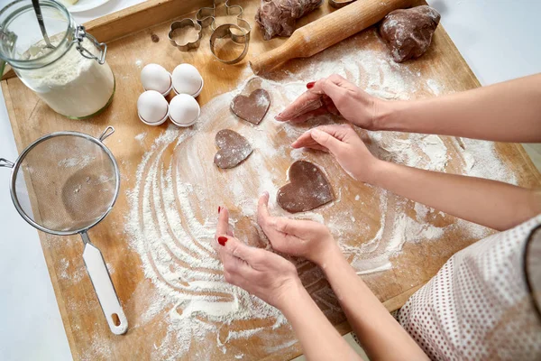 Manos de mamá e hija haciendo forma de corazón en el tablero de pastelería — Foto de Stock