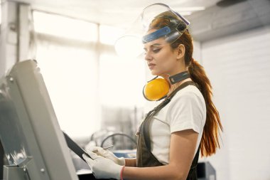 Bilgisayarlı makine ile fabrika üzerinde çalışan kadın mühendisi.