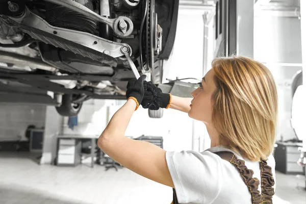 Blonde repairing auto undercarriage with wrench. — Stock Photo, Image