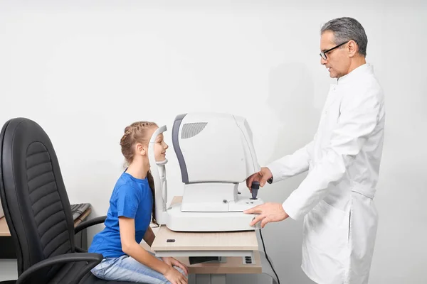 Gezichtsvermogen van een patiënt met de spleetlamp te onderzoeken van een optometrist. — Stockfoto