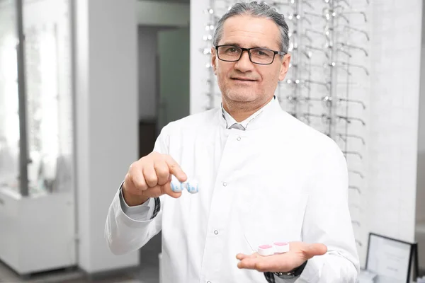 Augenarzt hält Behälter für Linsen im Behandlungsraum — Stockfoto