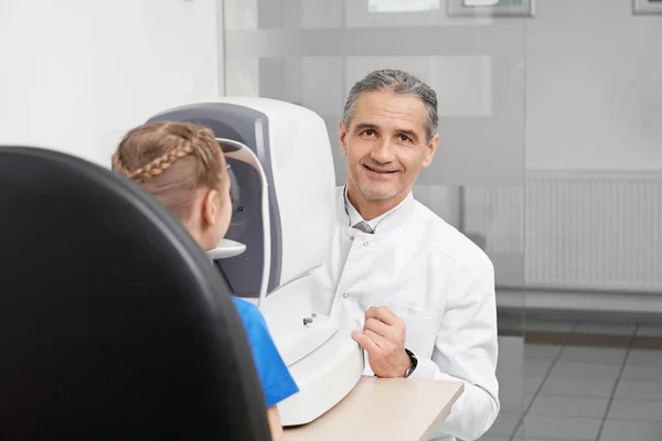 Dokter poseren, oog van de patiënt te testen met oog testmachine. — Stockfoto