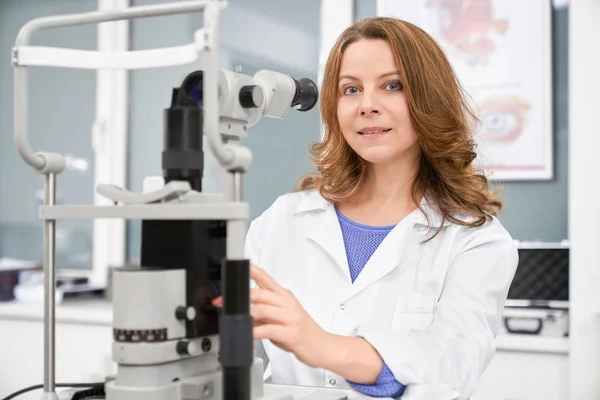 Ophtalmologiste femelle posant avec la machine d'essai d'oeil . — Photo