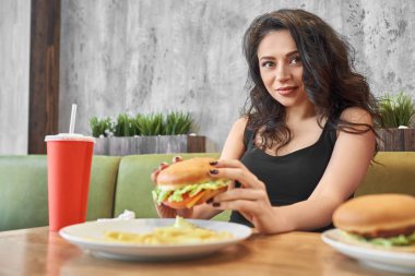 Esmer holding hamburger, kafede poz.