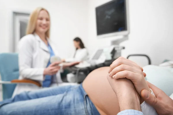 Man håller kvinnans hand under ultraljud diagnos. — Stockfoto