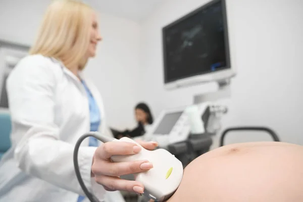 Orvos eszköz segítségével a terhes has ultrahang-vizsgálat. — Stock Fotó