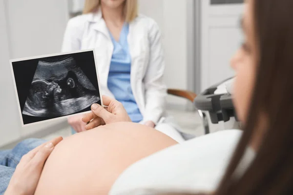 Femme enceinte tenant une radiographie, après consultation avec un médecin . — Photo