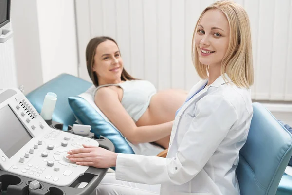 Medico e donna incinta in posa in gabinetto medico . — Foto Stock