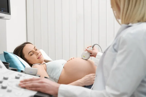 Médico haciendo ultrasonido examen de las mujeres embarazadas abdomen . — Foto de Stock