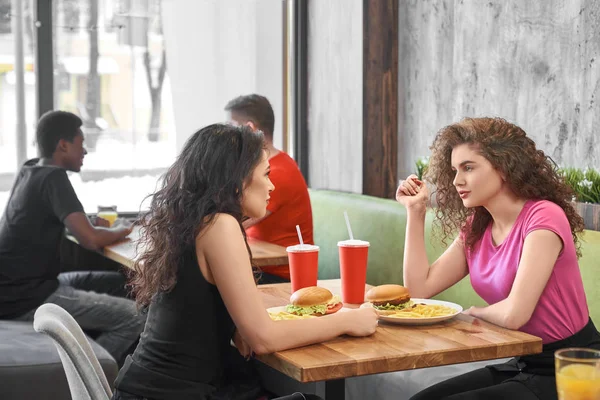 Mädchen sitzen im Café und essen Fast Food und kommunizieren. — Stockfoto