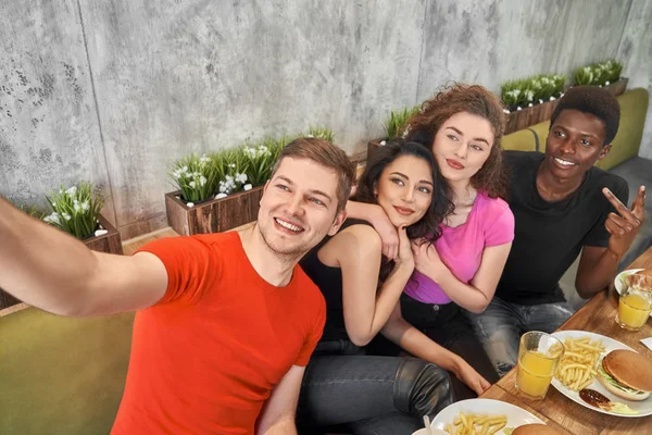 Amis faisant du selfie, assis ensemble dans un café . Image En Vente