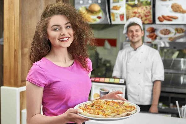 Hübsches Mädchen hält leckere Pizza in Pizzeria. — Stockfoto