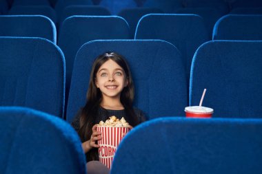 Güzel, mutlu kıza sinemada patlamış mısır ile film izlemek.