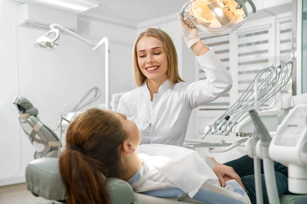 Kadın dişçi hasta ile konuşuyor koltuk üzerinde yatıyor — Stok fotoğraf