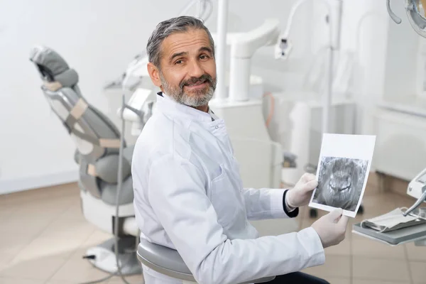 Профессиональный стоматолог позирует с рентгеном зубов в руках . — стоковое фото