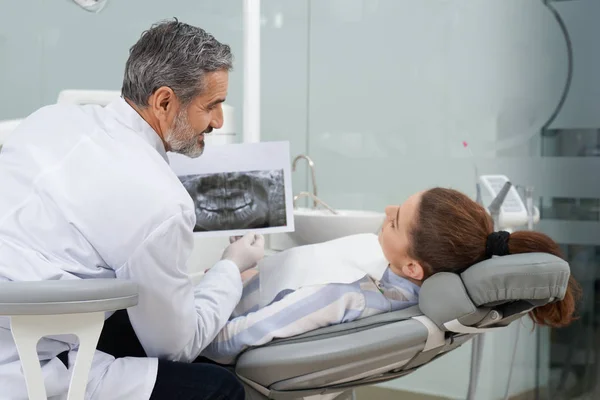 Estomatólogo mostrando radiografía dental al cliente . — Foto de Stock